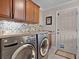 Modern laundry room featuring stainless steel washer and dryer, tiled backsplash, and custom cabinets at 749 Aberdeen Run, The Villages, FL 32162