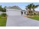 Charming single-story home featuring a manicured lawn with landscaping, a palm tree and a spacious two car garage at 7539 Hagemeyer Pl, The Villages, FL 34762