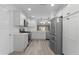 Modern white kitchen with stainless steel appliances and countertops overlooking living area at 7539 Hagemeyer Pl, The Villages, FL 34762