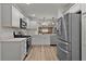 White kitchen featuring stainless steel appliances, quartz countertops, and luxury vinyl plank flooring at 7539 Hagemeyer Pl, The Villages, FL 34762