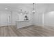 Bright living room blends seamlessly to kitchen area with modern lighting fixtures at 7539 Hagemeyer Pl, The Villages, FL 34762