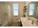 Bright bathroom featuring a shower/tub combo and large window with white blinds at 916 Carmillion Ct, Groveland, FL 34736