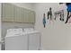 Functional laundry room featuring a modern washer and dryer with ample upper cabinet storage at 916 Carmillion Ct, Groveland, FL 34736