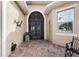 Elegant entrance with brick-paved patio, arched doorway, and decorative wall art at 10199 Mainsail Dr, Oxford, FL 34484