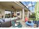 Spacious screened-in patio featuring multiple seating areas, colorful Adirondack chairs, and a view of the backyard at 10199 Mainsail Dr, Oxford, FL 34484