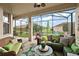 Relaxing screened lanai showcasing comfortable wicker seating, a decorative rug, and a view of the lush backyard at 10199 Mainsail Dr, Oxford, FL 34484