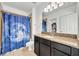 Bathroom featuring a granite vanity, walk-in shower with decorative blue curtain and tile surround at 10219 Lenox St, Clermont, FL 34711