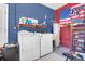 Functional laundry room with washer, dryer, and storage, accented by patriotic decor at 10640 Parkway Dr, Clermont, FL 34711