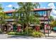 Charming outdoor dining area with umbrellas and greenery under a building with large windows and a red roof at 110 N Tremain St # 205, Mount Dora, FL 32757