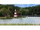 Scenic view of the lakeside park featuring a red and white striped lighthouse and a wooden pier with a gazebo at 110 N Tremain St # 205, Mount Dora, FL 32757