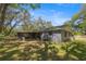 Back exterior view with a screened in porch and mature trees and landscaping at 1107 Valley Rd, Fruitland Park, FL 34731