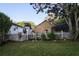 Scenic backyard with a white picket fence, mature trees, and lush lawn creating a serene and private outdoor space at 11312 Haskell Dr, Clermont, FL 34711