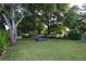 Expansive backyard with lush greenery, mature trees, and white picket fence offering privacy and space for outdoor activities at 11312 Haskell Dr, Clermont, FL 34711