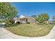 Well-manicured front yard features lush green grass, mature trees, and a charming screened-in porch at 117 Falling Acorn Ave, Groveland, FL 34736