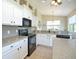 Well-equipped kitchen with white cabinetry, granite countertops and modern black appliances at 117 Falling Acorn Ave, Groveland, FL 34736