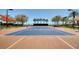Outdoor tennis court featuring a well-maintained surface, surrounding trees, and shaded viewing areas for spectators at 117 Falling Acorn Ave, Groveland, FL 34736