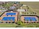 Aerial view of community tennis courts and bocce ball courts near a clubhouse at 117 Falling Acorn Ave, Groveland, FL 34736