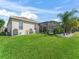 Large grassy backyard with a screened-in pool area, mature foliage, and views of the adjacent golf course at 12136 Se 176Th Loop, Summerfield, FL 34491