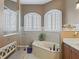 Bright bathroom featuring a soaking tub with tiled surround and arched windows for natural light and ventilation at 12136 Se 176Th Loop, Summerfield, FL 34491