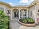 Inviting front porch with decorative columns, a beautifully landscaped flower bed, and decorative light fixtures at 12136 Se 176Th Loop, Summerfield, FL 34491