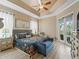 Cozy main bedroom featuring tray ceilings, a comfortable bed with decorative pillows, and private patio access at 12136 Se 176Th Loop, Summerfield, FL 34491