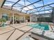 Screened-in pool area featuring an integrated hot tub, outdoor dining area, and relaxing lounge chairs at 12136 Se 176Th Loop, Summerfield, FL 34491