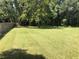 Large, well-maintained grassy backyard featuring a wooden fence and mature trees for shade and privacy at 136 S Commercial St, Coleman, FL 33521