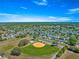Aerial view of neighborhood baseball field and green lawns on a bright sunny day at 17594 Se 95Th Cir, Summerfield, FL 34491