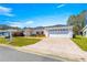 Single-story home with long paved driveway and well-manicured lawn, brick accents, and an attached two-car garage at 17594 Se 95Th Cir, Summerfield, FL 34491