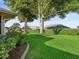 Green backyard featuring lush landscaping, large shade trees and manicured lawn creates a peaceful outdoor space at 17898 Se 125Th Cir, Summerfield, FL 34491