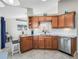 Spacious kitchen featuring stainless steel appliances, light granite countertops, wood cabinets, and view to adjacent living room at 17898 Se 125Th Cir, Summerfield, FL 34491