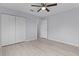 A bedroom with wood-look flooring, ceiling fan, and doors leading to closets and hallways at 17965 Se 107Th Ct, Summerfield, FL 34491