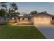 Charming single-story home with well-manicured lawn, gray siding, and a two-car garage at dusk at 17965 Se 107Th Ct, Summerfield, FL 34491