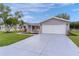 A tidy single-story home with a well-maintained lawn, gray siding, and an attached two-car garage at 17965 Se 107Th Ct, Summerfield, FL 34491