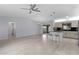 Open-concept living space with modern light fixtures, light gray flooring, and views into the kitchen at 17965 Se 107Th Ct, Summerfield, FL 34491