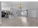 Inviting open-concept living space with kitchen island, light gray flooring, and a charming chandelier at 17965 Se 107Th Ct, Summerfield, FL 34491
