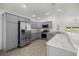 Modern gray kitchen boasts stainless steel appliances, stone countertops, and ample cabinet space at 1853 Pasqua Pl, The Villages, FL 32163
