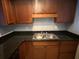 This cozy kitchen offers dark counters, wooden cabinets, and a stainless steel sink at 1928 Conway Rd # 23, Orlando, FL 32812