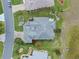 Aerial view of a gray roof home with green backyard, palm trees, and lush landscaping at 22247 Draw Bridge Dr, Leesburg, FL 34748
