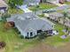 Aerial view of a home with gray roof, screened patio, and lush landscaping in a quiet neighborhood at 22247 Draw Bridge Dr, Leesburg, FL 34748