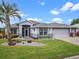 Single-story home featuring a two-car garage, a screened entry, lush landscaping, and a manicured front yard at 22247 Draw Bridge Dr, Leesburg, FL 34748