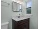 Bathroom vanity with marble countertop, dark wood cabinets, framed mirror, and modern lighting at 234 S Central Ave, Apopka, FL 32703