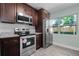 Modern kitchen with stainless steel appliances, granite counters, and cherry wood cabinets at 234 S Central Ave, Apopka, FL 32703