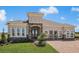 Stunning single-story home with stone accents, arched windows, and meticulously landscaped front yard with brick-paved driveway at 2408 Juniper Berry Dr, Minneola, FL 34715