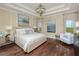 Serene main bedroom boasts coffered ceiling, hardwood floors, designer lighting, and elegant decor with comfortable seating at 2408 Juniper Berry Dr, Minneola, FL 34715