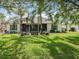 Expansive backyard with green grass, palm trees, and a screened-in patio, perfect for relaxation and entertainment at 24112 Robinwood St, Leesburg, FL 34748