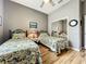 Cozy bedroom featuring two twin beds, wood laminate flooring, ceiling fan, and mirrored closet doors at 24112 Robinwood St, Leesburg, FL 34748