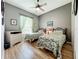This bedroom has wood laminate flooring, ceiling fan, dresser, and a bright window with light green curtains at 24112 Robinwood St, Leesburg, FL 34748