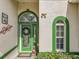 Close-up of a decorative green front door with glass details, wreath, and plants at 24112 Robinwood St, Leesburg, FL 34748