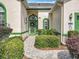 Inviting front entrance featuring a decorative green door and lush landscaping with well-maintained plants at 24112 Robinwood St, Leesburg, FL 34748